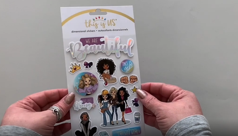 Female hands pick up and show front and back of 3D scrapbook stickers with package, featuring colorful illustrations of a diverse group of women with foil accents.