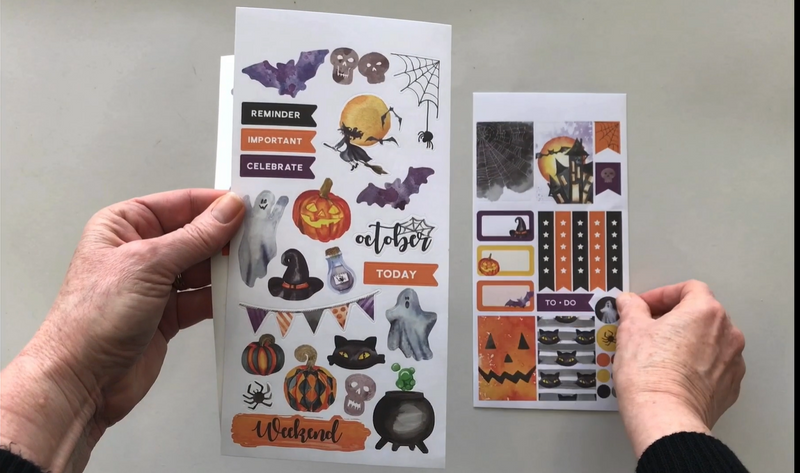 Female hands pick up and show in detail 3 sheets of planner stickers featuring halloween.