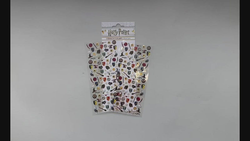 Female hands pick up and display in detail micro stickers featuring Harry Potter ™ crests, sorting hats and symbols.