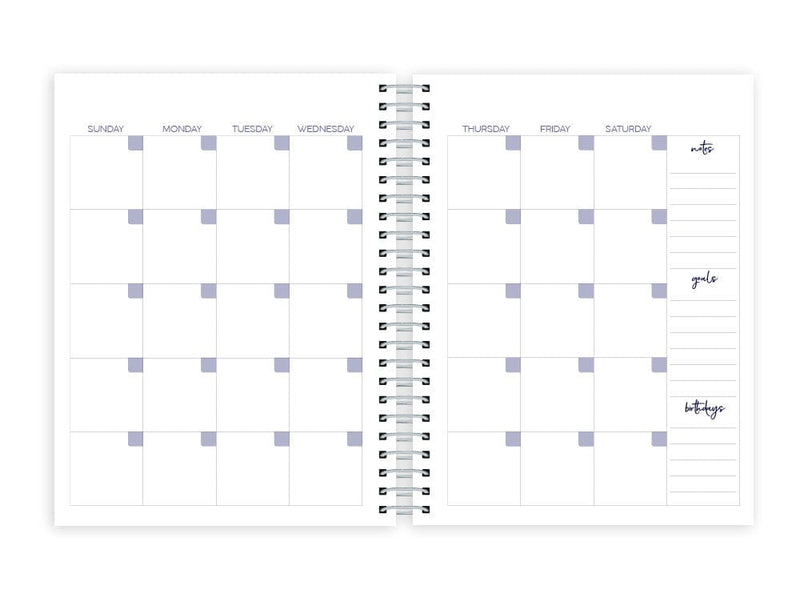 weekly planner featuring monthly spread with silver coil spine, shown on white background.