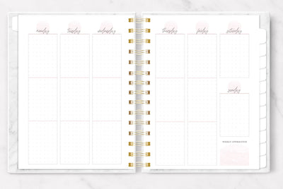 Weekly planner shown open to a light pink and white, dot grid, vertical weekly page spread.