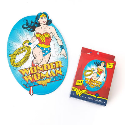 mini die cut jigsaw puzzle featuring wonder woman on a bright blue background, shown with package on a white background.