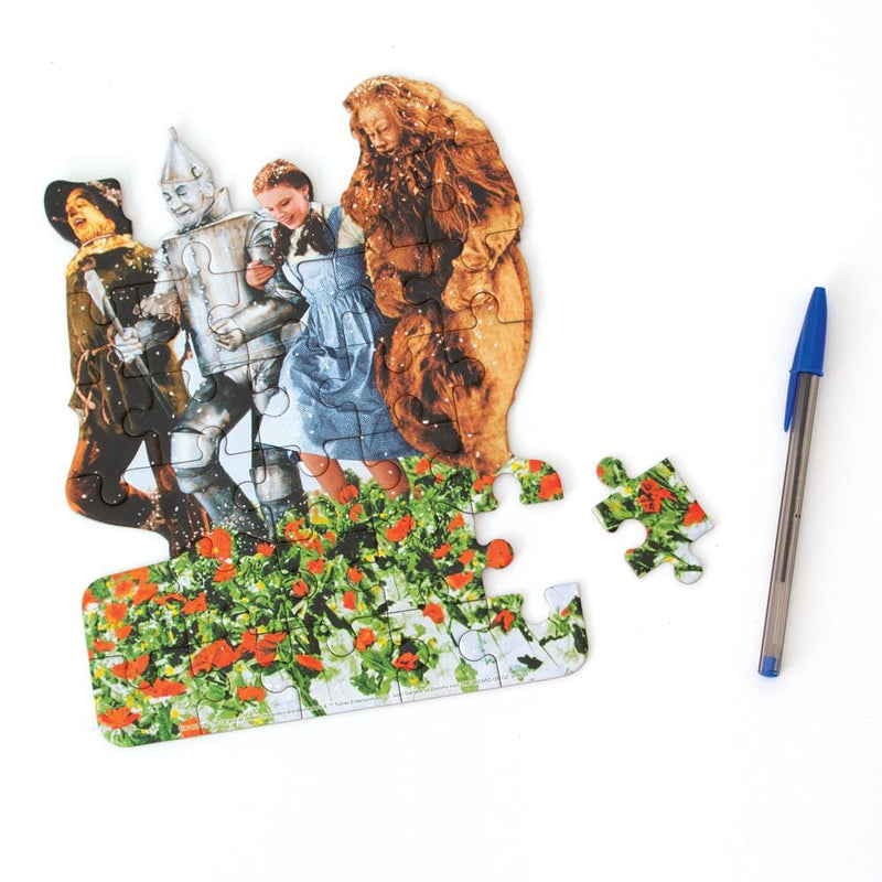 die cut mini jigsaw puzzle featuring The Wizard of Oz characters, shown with pen and one separate piece on white background.
