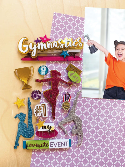 3D scrapbook stickers featuring glitter gymnastics silhouettes shown next to a photo of a child with a trophy on a patterned background.