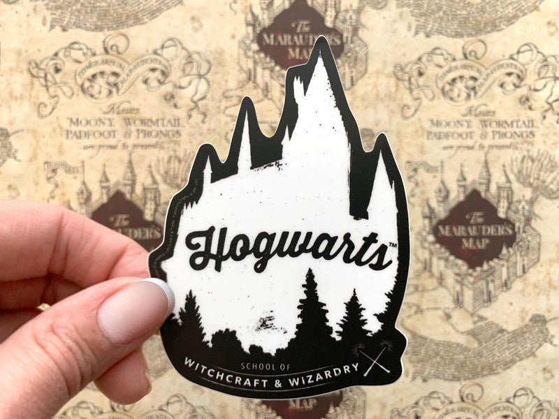close up of shaped Harry Potter laptop sticker featuring a silhouette of the Hogwarts castle in black and white, shown in hand above a marauder&