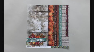 Female hands pick up scrapbook paper featuring wood pattern and pumpkins on one side and an illustrated leaf pattern on the other side.