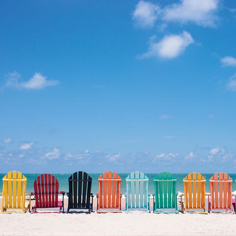 scrapbook paper featuring a photographic image of a row of colorful chairs along the beach.
