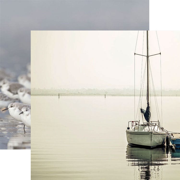 scrapbook paper featuring a light gray photographic image of a body of water with a sailboat docked in the foreground shown overlapping an image of birds at the shore.