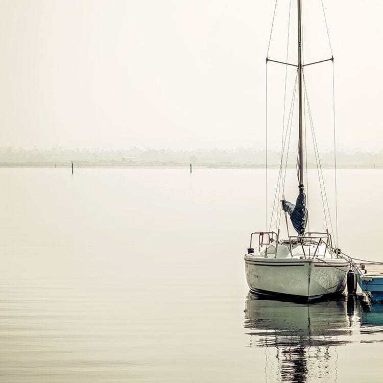 scrapbook paper featuring a light gray photographic image of a body of water with a sailboat docked in the foreground.
