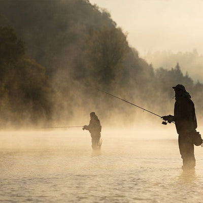 scrapbook paper featuring a misty photographic image of two anglers fishing in a stream.