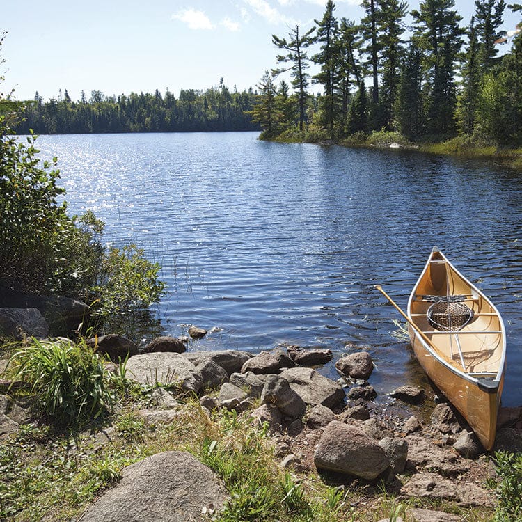 scrapbook paper featuring a photographic image of a canoe resting on a rocky shore at a lake