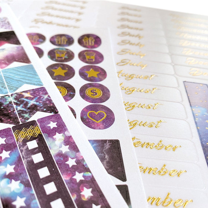 PL-2018E - Weekly Planner - Undated Stargazer - Purple and gold stargazer-themed planner pages with decorative stickers and month tabs visible