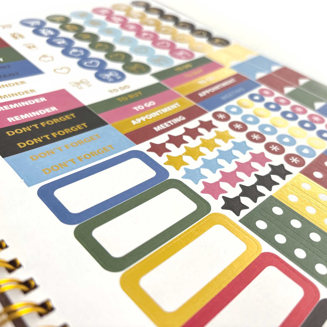 PL-2040E - Through the Keyhole 12 Month Undated Planner - Colorful undated planner pages featuring reminder stickers, star decorations, checkbox dots, and labeled sections in blue, green, yellow, pink, and neutral tones