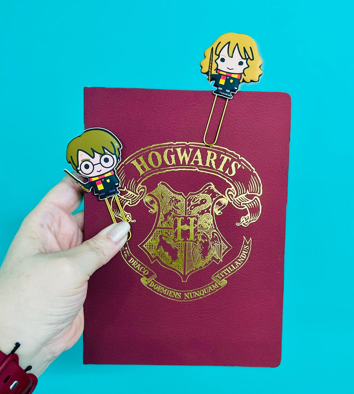 PLPC-0011E - Planner Bookmark Set - Harry and Hermione Puffy - Two Harry Potter character bookmarks displayed with a burgundy Hogwarts crest notebook against a turquoise background