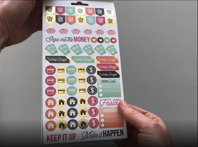 Female hands pick up and flip through the pages of the "Budgeting" planner stickers booklet to show each page of stickers in detail. There are four pages in this sticker book by Paper House Productions.