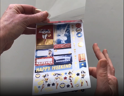 Female hands pick up and flip through the pages of the "Wonder Woman" planner stickers booklet to show each page of stickers in detail. There are four pages in this sticker book by Paper House Productions.