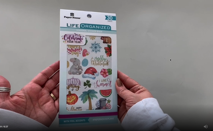 Female hands pick up and flip through the pages of the "Celebrate Your Year" planner stickers booklet to show each page of holiday and birthday stickers in detail. There are thirty pages in this sticker book by Paper House Productions.