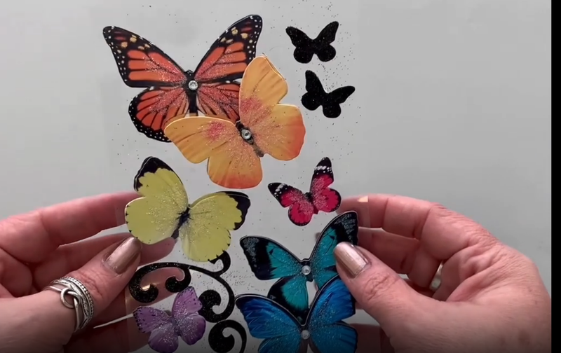 Female hands pick up and show front and back of photo real 3D decorative stickers featuring colorful butterflies.