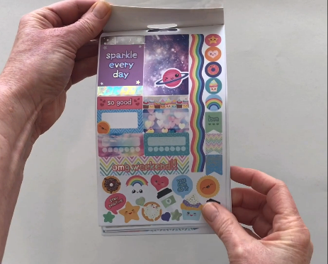 Female hands pick up and flip through the pages of the "Kawaii Not" planner stickers booklet to show each page of stickers in detail. There are four pages in this sticker book by Paper House Productions.