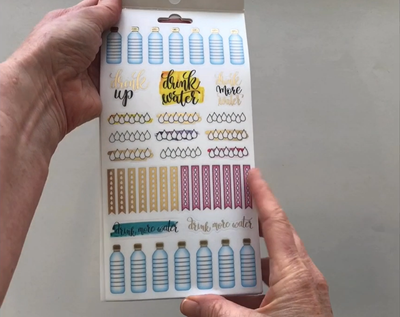 Female hands pick up and flip through the pages of the "Creative-Trackers" planner stickers booklet to show each page of stickers in detail. There are four pages in this sticker book by Paper House Productions.