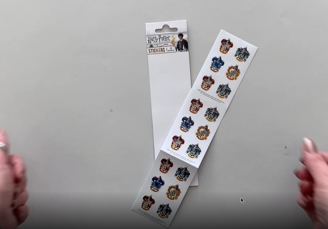 Female hands pick up and show in detail stickers featuring the Harry Potter crests..