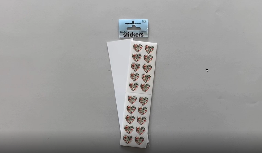 Female hands pick up and show in detail stickers featuring floral hearts.