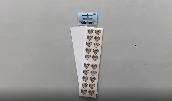 Female hands pick up and show in detail stickers featuring floral hearts.