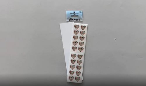 Female hands pick up and show in detail stickers featuring floral hearts.