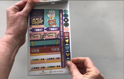 Female hands pick up and flip through the pages of the "Hustle for Justice" planner stickers booklet to show each page of stickers in detail. There are four pages in this sticker book by Paper House Productions.