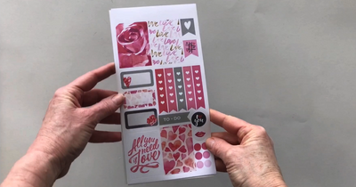 Female hands pick up 3 sheets of planner stickers and shows front and back in detail featuring Valentine's Day illustrations and words.