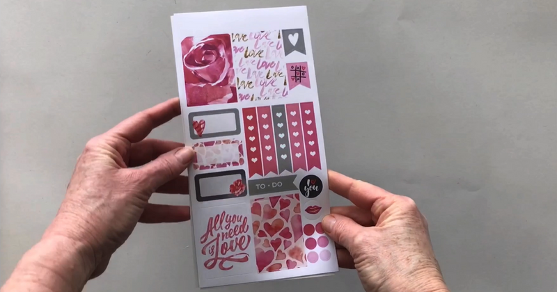 Female hands pick up 3 sheets of planner stickers and shows front and back in detail featuring Valentine&