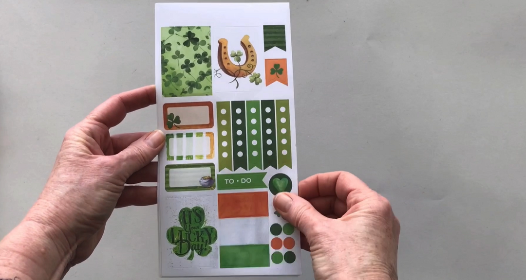 Female hands pick up and show 3 sheets of stickers in detail featuring St. Patrick&