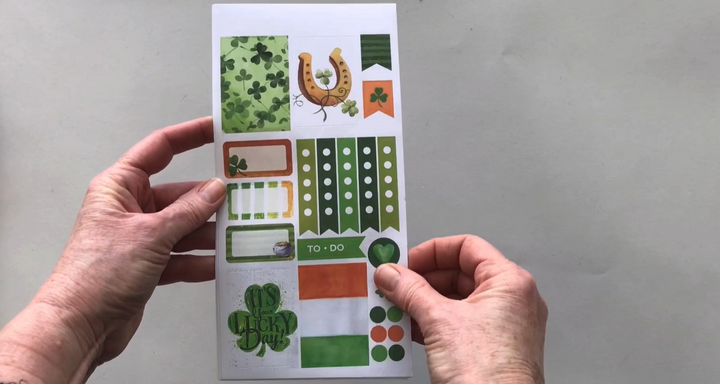Female hands pick up and show 3 sheets of stickers in detail featuring St. Patrick&