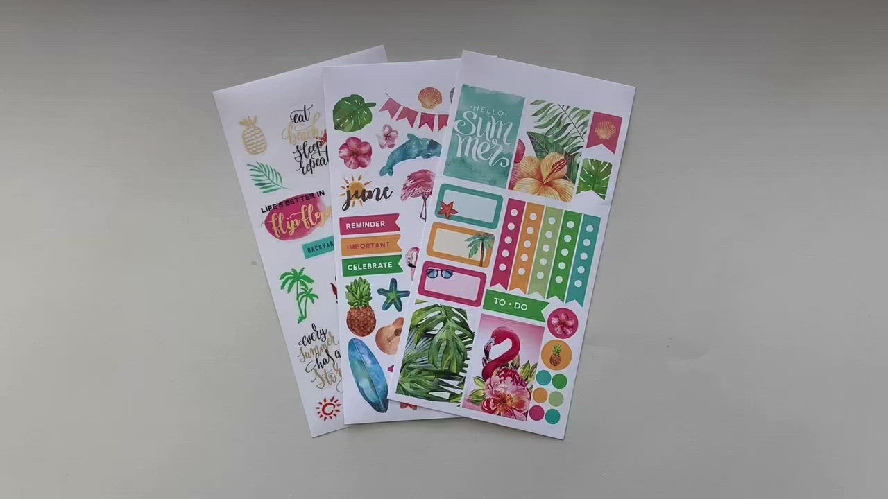 Female hands pick up and show in detail 3 sheets of stickers featuring a tropical June theme.