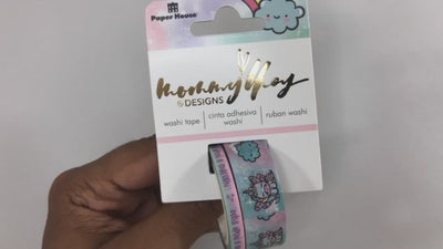 Hand picks up package of washi tape set and shows the 2 pastel colored tapes featuring pastel unicorns and text.