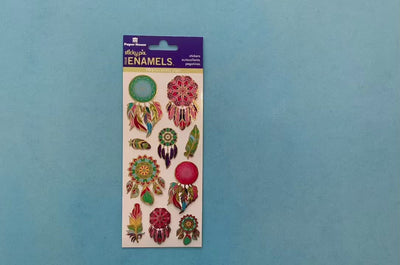 female hands display foil stickers featuring colorful dreamcatchers with gold details, on blue background with package.