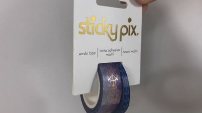 Hand picks up washi tape set in package featuring a starry blue sky with gold accents on one roll and a white moon pattern on blue on the other roll.