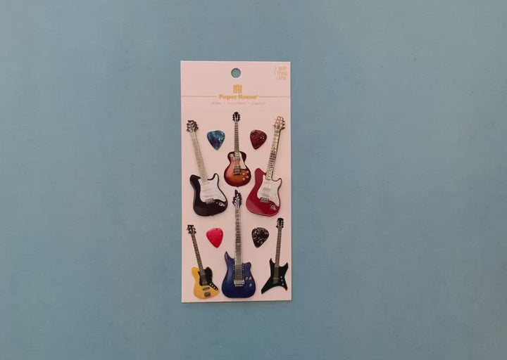 female hands display  scrapbook stickers featuring colorful electric guitars, and shows close up of 2 individual stickers.