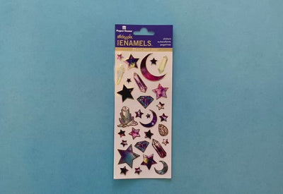 female hands display foil stickers featuring illustrated celestial stars, crystals and moons with gold details