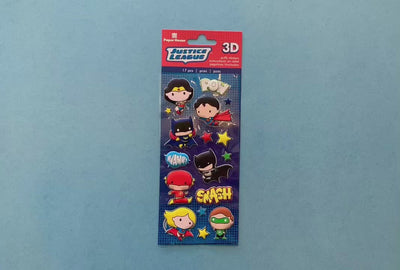 female hands displaying puffy stickers featuring Justice League chibi characters, on blue background with package.