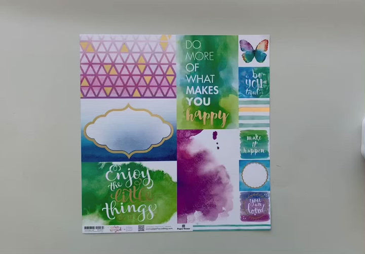 Female hands displaying both sides of a colorful, tag watercolor scrapbook paper with a teal and white striped pattern on the reverse.