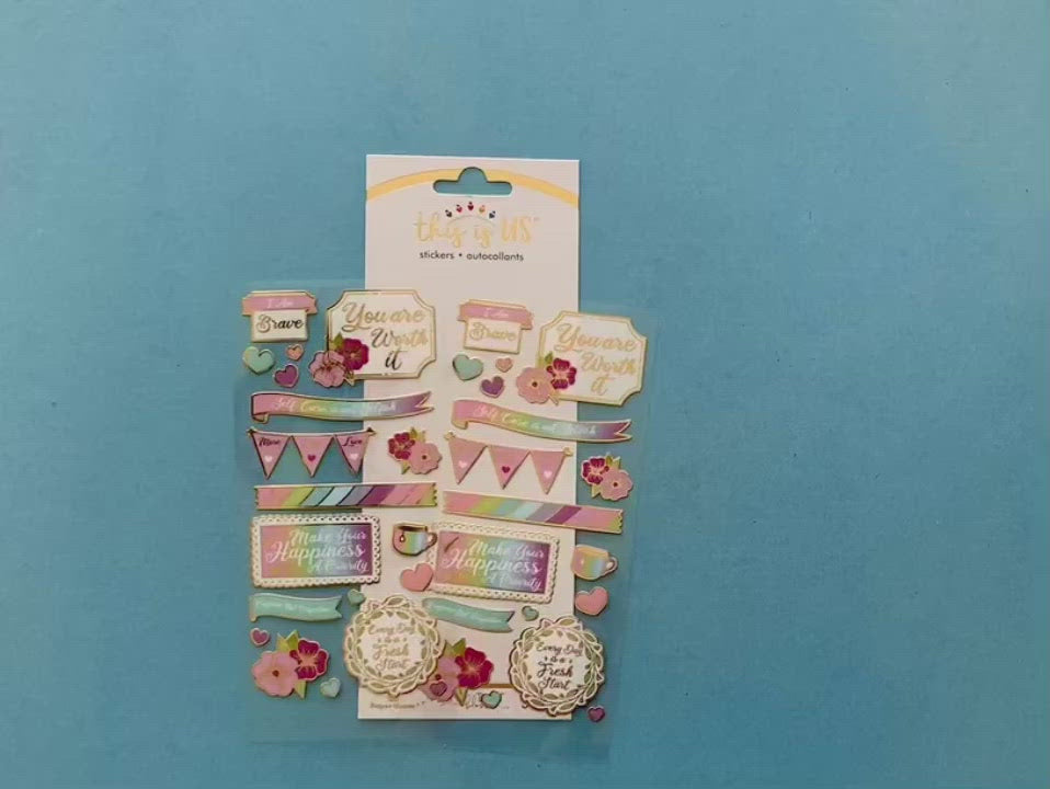 female hands display 2 sheets of foil stickers featuring illustrated flowers, hearts and self-care illustrations with gold details and shows a close up one of the stickers