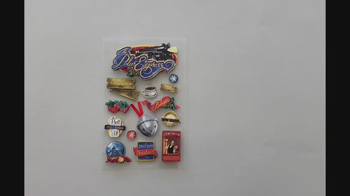 Female hands pick up and show front and back details of 3D scrapbook stickers featuring Polar Express icons from the story book.