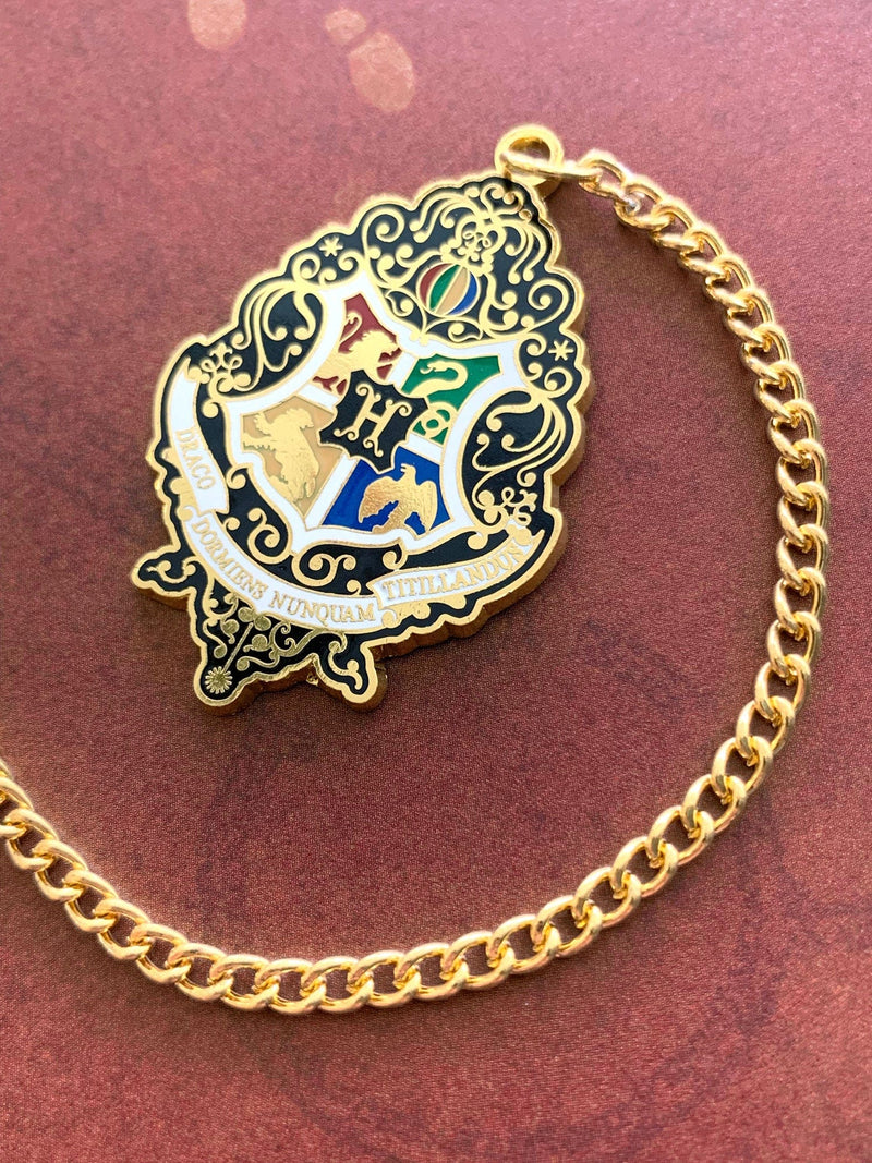 Harry Potter bookmark featuring colorful crest with gold details and gold chain, shown on rust colored background.