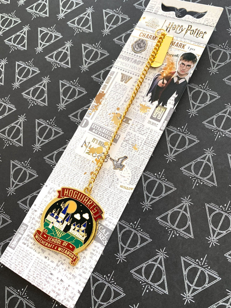 Harry Potter bookmark featuring colorful , round charm of illustrated Hogwarts castle, shown on gold chain, shown in package on black and white patterned background.