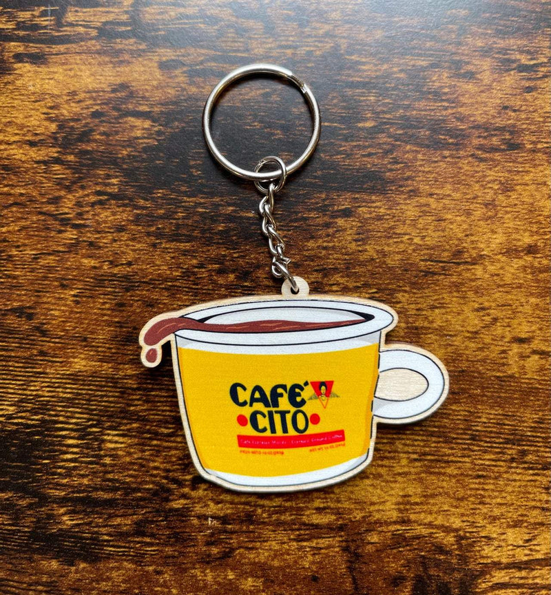 cute keychain featuring cafecito illustration, shown on wooden background.