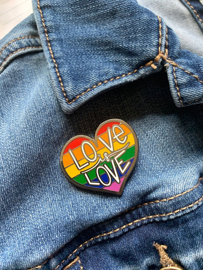 Love is Love enamel pin made of enamel and silver shown being used as a jacket pin on denim.
