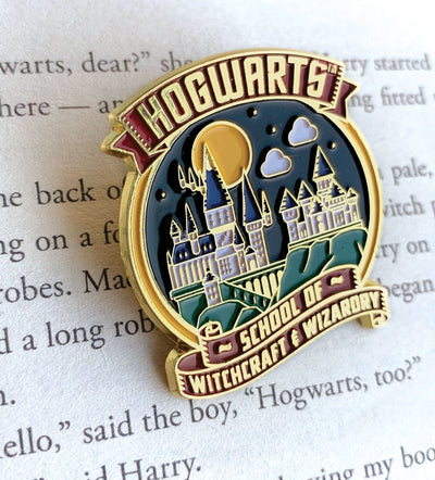 Harry Potter Hogwarts enamel pin shown on a page of text from a Harry Potter novel.
