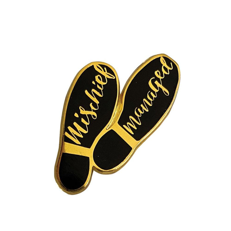 enamel pin featuring the words, Mischief Managed on the soles of shoes with black and gold details.
