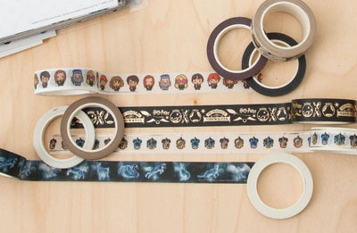 6 rolls of Harry Potter ™ washi tape are shown on wood surface with 4 strips featuring chibi, patronus, crests and quidditch symbols.